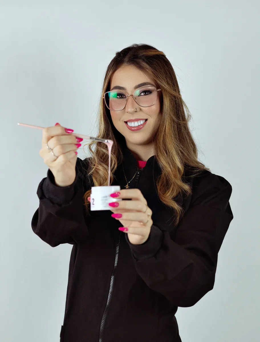 Valentina sonriendo, con un pincel y un bote de gel para uñas en las manos.
